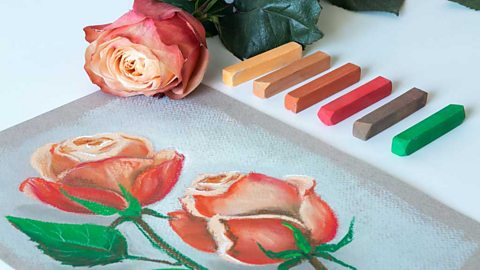 A pastel drawing of two pink roses with six pastel sticks lined up next to it