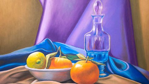 Pastel drawing of oranges, a lemon and glass carafe with colourful cloths as a backdrop