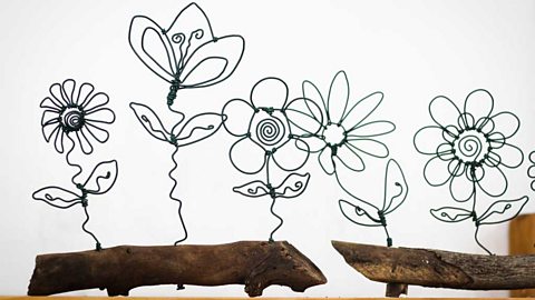 Wire sculptures of flowers set in logs