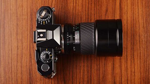 A view from above of a black SLR camera on a wooden surface