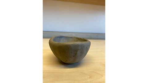 A basic unfinished bowl made out of clay on a table