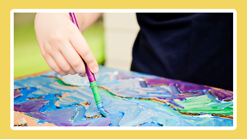 A child's hand painting with a brush.