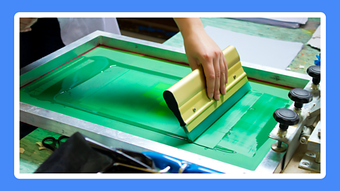 A hand holding a squeegee over a painting surface.