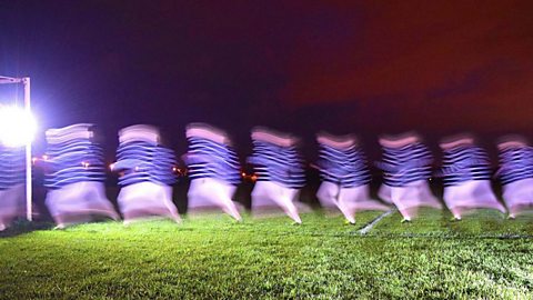 Blurred photograph of a line of running footballers in the dark