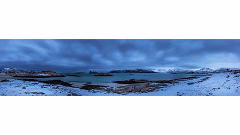 An arctic scene. Snow, rocks, frozen sea and hills