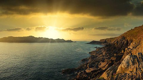 Coastal scene. Rocky cliffs and sun shining over an island