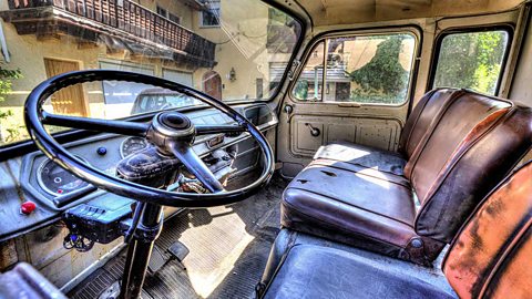 Interior of an old fashioned car. Lots of scuffs and torn leather seats