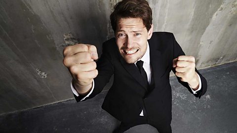 A man in a suit clenching his fists