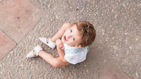 A young child sat on the pavement