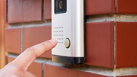 A finger rings a doorbell.