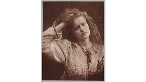 A dusty-red tinted photograph showing a girl with one hand in her hair, looking at the camera. 