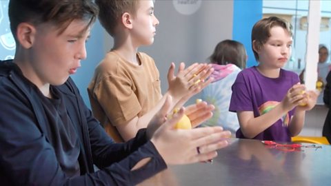 Kids rolling lemons in their hands.