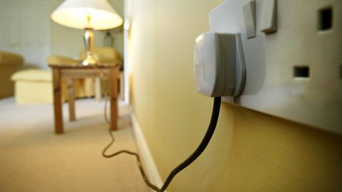 A household socket with a plug and wire leading to a lamp, which is switched 'on'