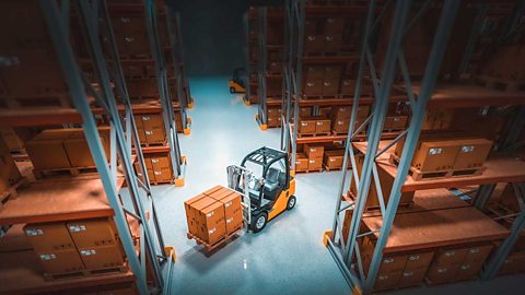 Forklift in a warehouse lifting brown boxes