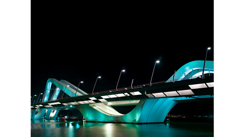 A curving bridge lit up with blue and white lights.