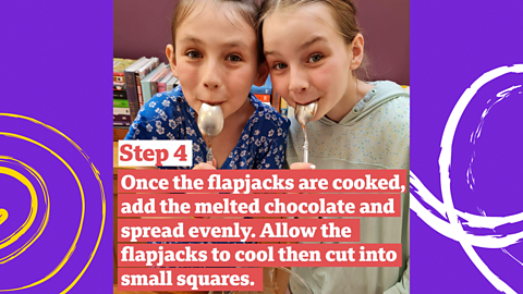 Two young girls licking chocolate off spoons.