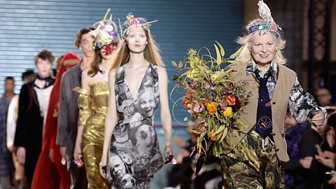 Vivienne Westwood, holding a bouquet of flowers, followed by a line of models.