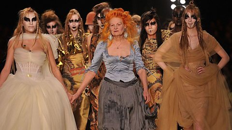 Vivienne Westwood wearing blue and black, surrounded by models wearing her designs.