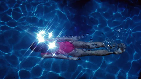 A woman swimming underwater in a pink costume (Credit: Alamy)