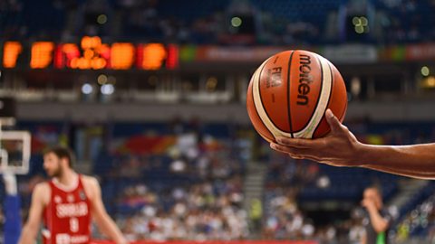 A basketball balanced on a player's hand during a game.