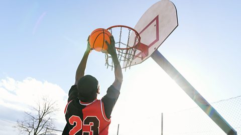 A basketball player jumps up to score a hoop 