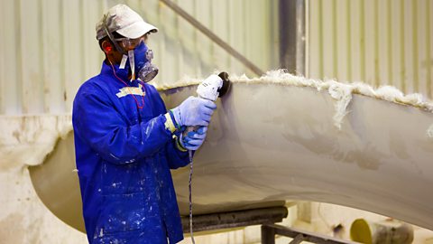 Man with protective gear grinding glass fiber surface