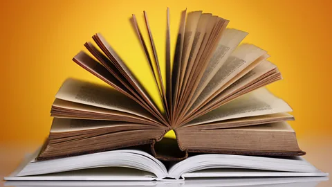 Two hardback books lying open on a table