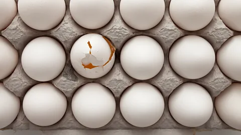 One broken egg in a box surrounded by unbroken eggs (Credit: Getty Images)