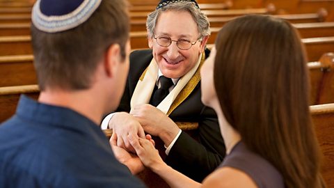 A rabbi can be seen in the middle of the photo, with the backs of the heads of a couple either side of the frame.