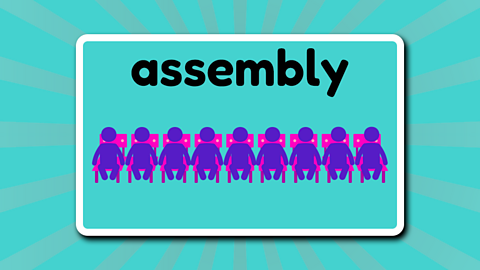 A row of people sat in chairs beneath the word 'assembly'