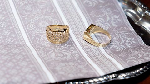 Two gold wedding rings on a cloth.