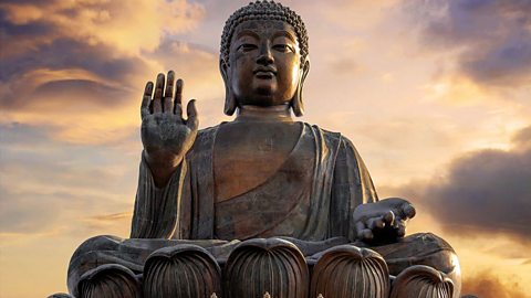 A statue of The Buddha, with right hand raised.