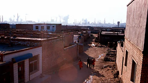 A family walks through a neighbourhood near a steel mill in China (Credit: Getty Images)