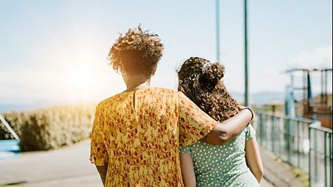 A mother with her arm around her daughter's shoulders.