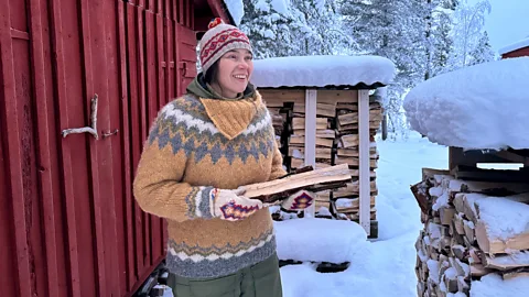 Anna Morottaja holds some firewood outside her wood store (Credit: Riikka Morottaja)