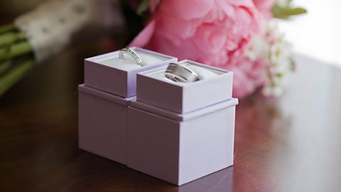 Two wedding rings in boxes lying on a table.