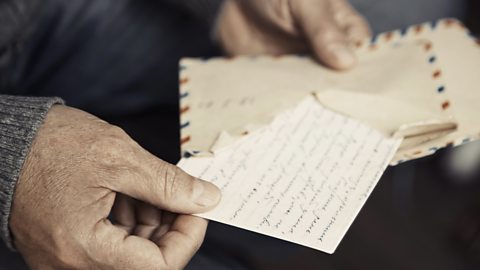 A man holding an open letter and reading the handwritten contents.