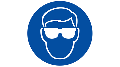 Blue circle surrounding diagram of a head wearing eye protection
