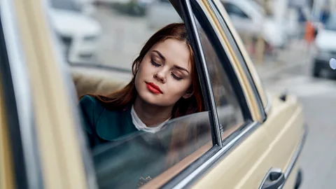 Young woman sleeping in back of car (Credit: Getty Images)