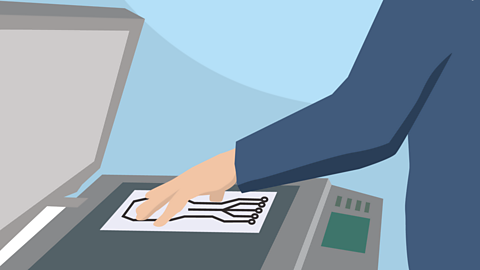 Hand placing a drawing of a circuit on the glass of a photocopier