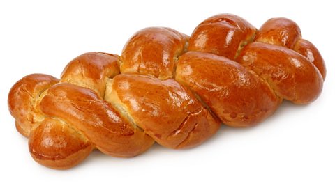 A loaf of glazed bread plaited on a white background