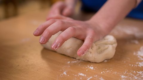 The palm of a child's hands pushing down of the dough