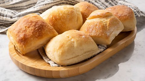 Six ciabatta bread buns on a wooden tray