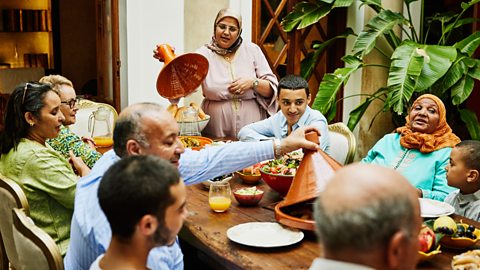 A multigenerational family sit around a table sharing a meal