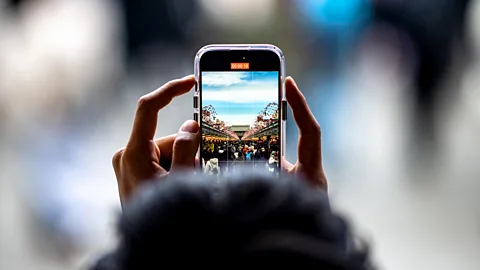 A person uses a mobile phone to film the shopping street at Asakusa district near Sensoji Temple, a popular tourist location, in Tokyo on January 18, 2024 (Credit: Getty Images)