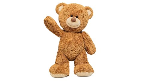 A teddy bear toy with its right arm up in the air