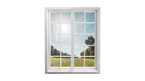 A white paned window with green grass, blue sky and trees in the background