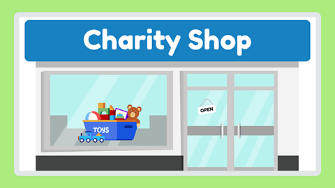 An illustration of a charity shop window. In the window is a blue box full of donated toys. 