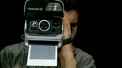 A man holding a polaroid camera