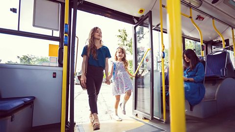  A mother and her daughter entering a bus with open doors